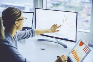 Business woman study financial market to calculate possible risks and profits.Female economist accounting money with statistics graphs pointing on screen of computer at desktop. Quotations on exchange