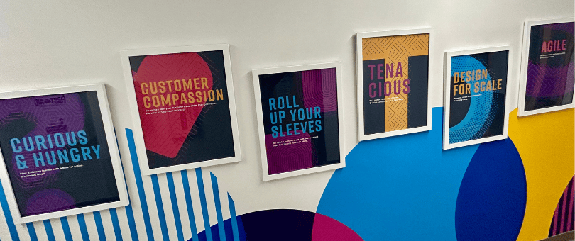 Signifyd's wall of values, a colorful wall — brand colors — with framed values messages spanning a corridor