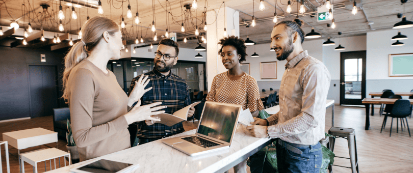 Retail-specific fraud experts conferring around a laptop in a modern office.