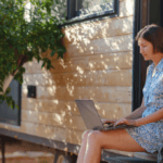 A woman sitting in a warm backyard shopping on a laptop for holiday predictions post