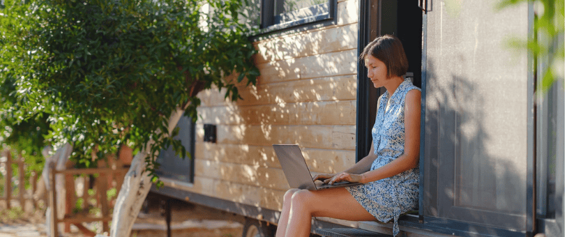 A woman sitting in a warm backyard shopping on a laptop for holiday predictions post