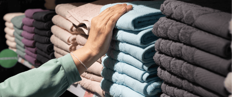 Person shopping for towels, checking wiht her hand the texture of one brand