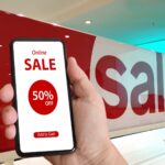 shopper with a mobile device displaying 50% off sale in forefront of big 