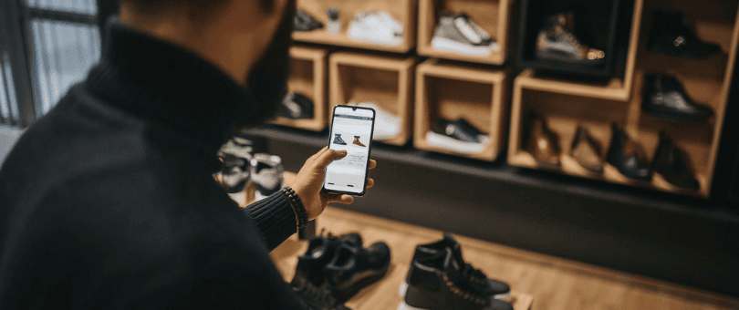 Man shopping for shoes, doing price comparison on his phone