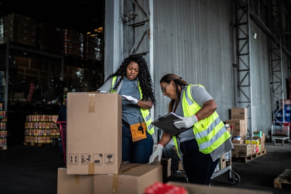 two female warehouse workers checking in returned packages for Signifyd post on returns fraud & abuse