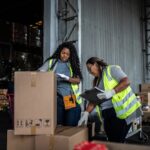 two female warehouse workers checking in returned packages for Signifyd post on returns fraud & abuse