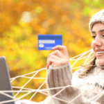 A woman in stocking cap and cozy sweater relaxed and shopping online in a hammock