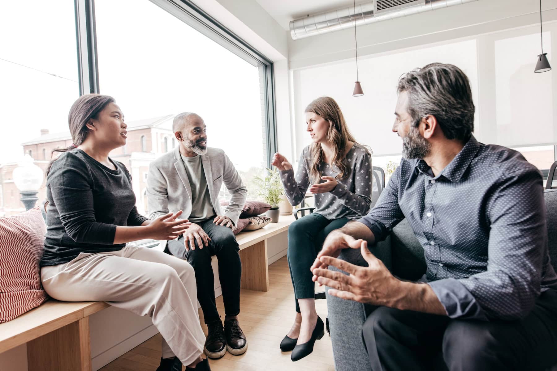 Group of sales people sitting in light-filled room dicussing sales strategy